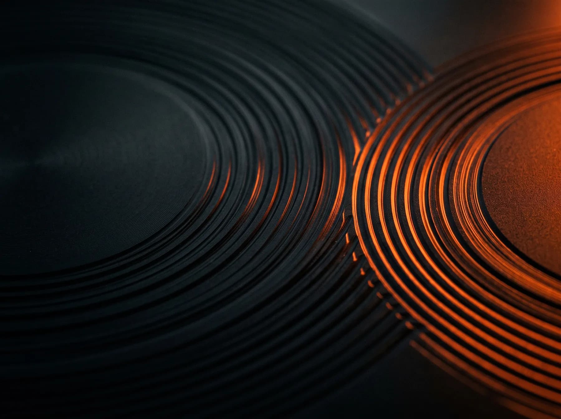 Macro photograph of a machined black metal surface catching an orange rim light